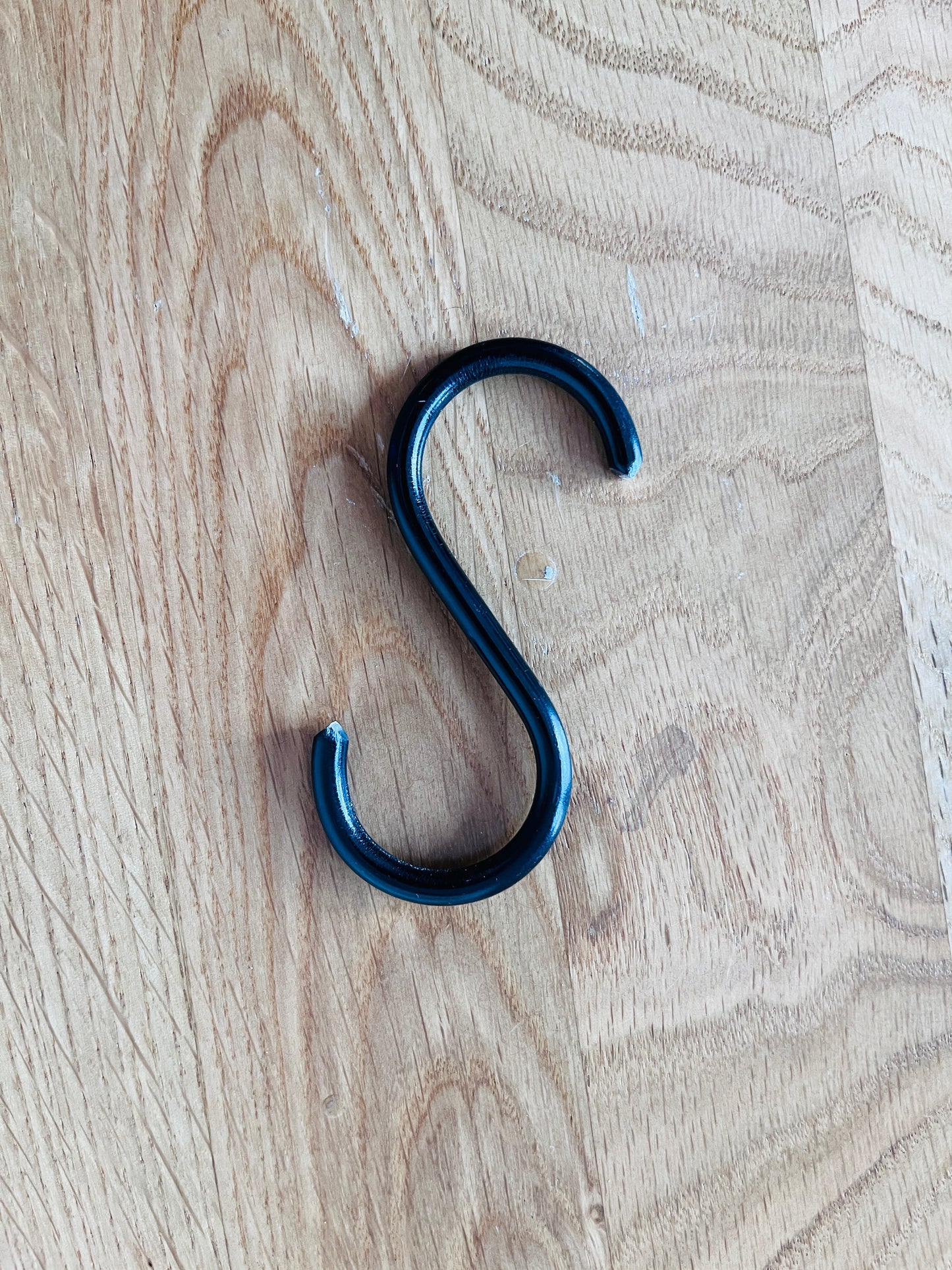 Black metal S-hook on a wooden surface