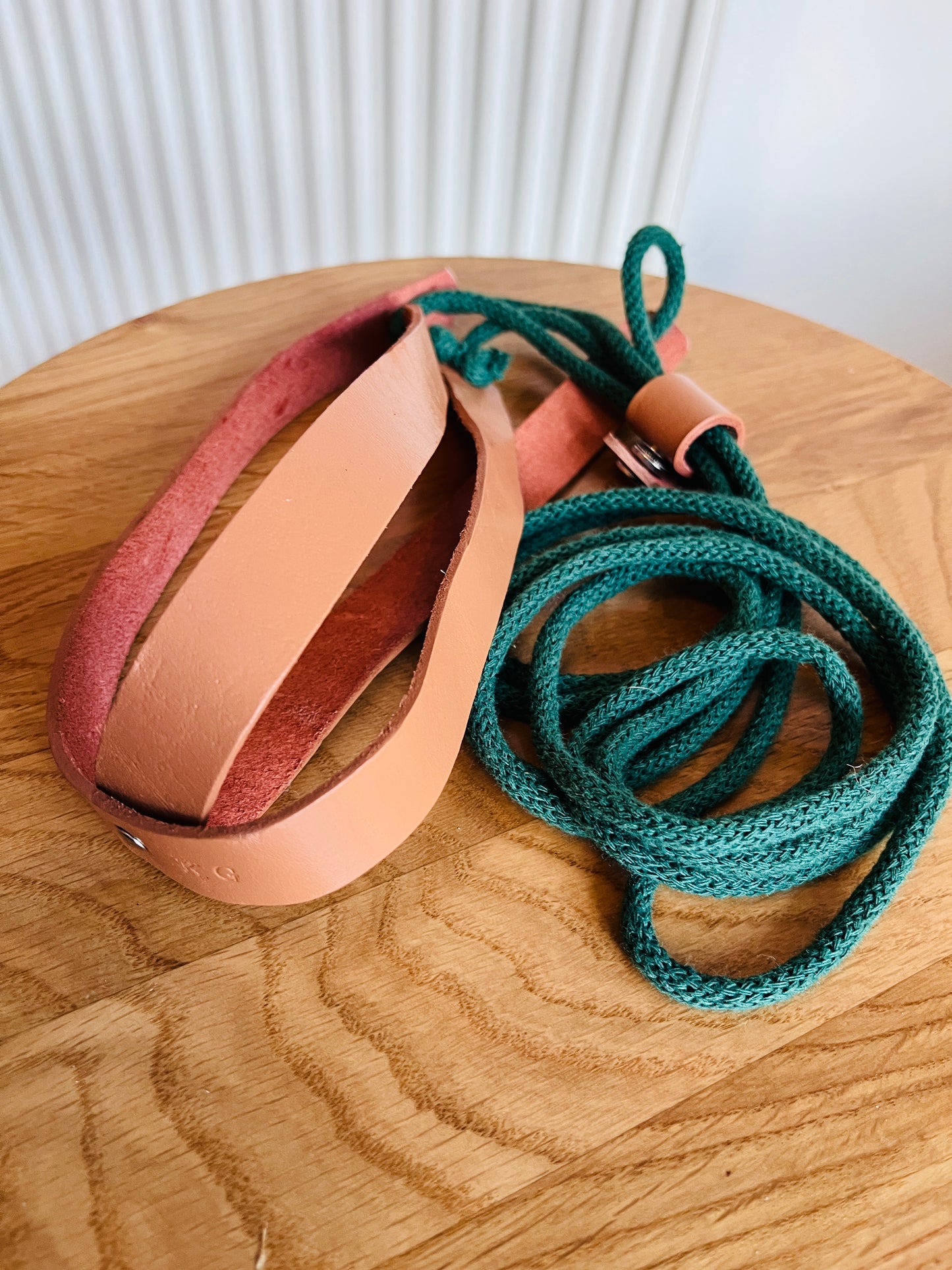 Leather plant hanger with green cotton cord on a wooden surface