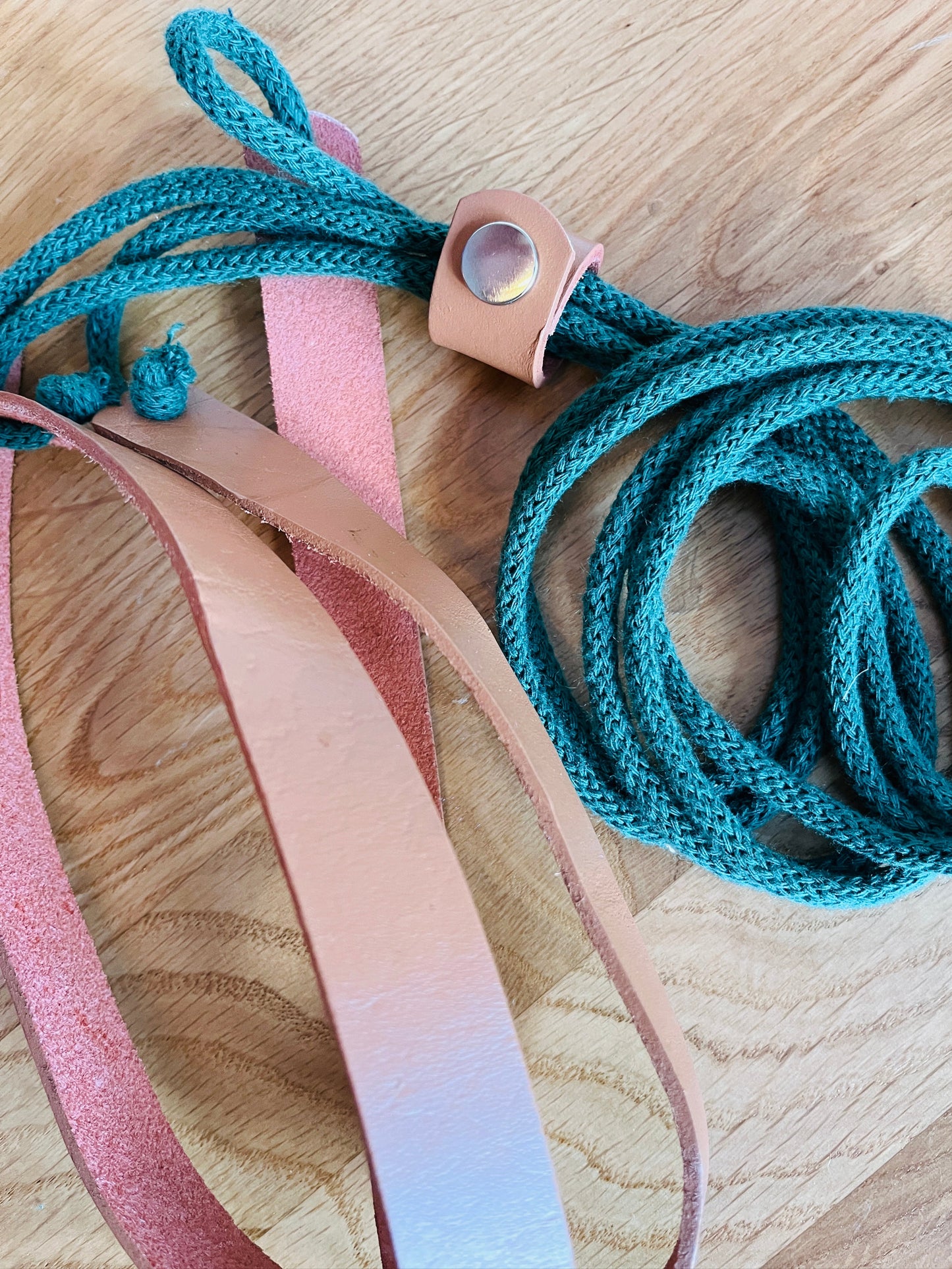 Green cotton cord and leather plant hanger on a wooden surface