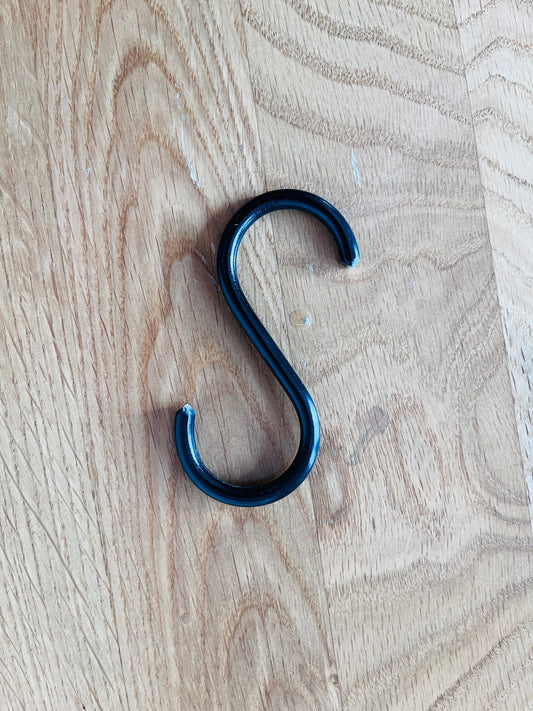 Black metal S-hook on a wooden surface