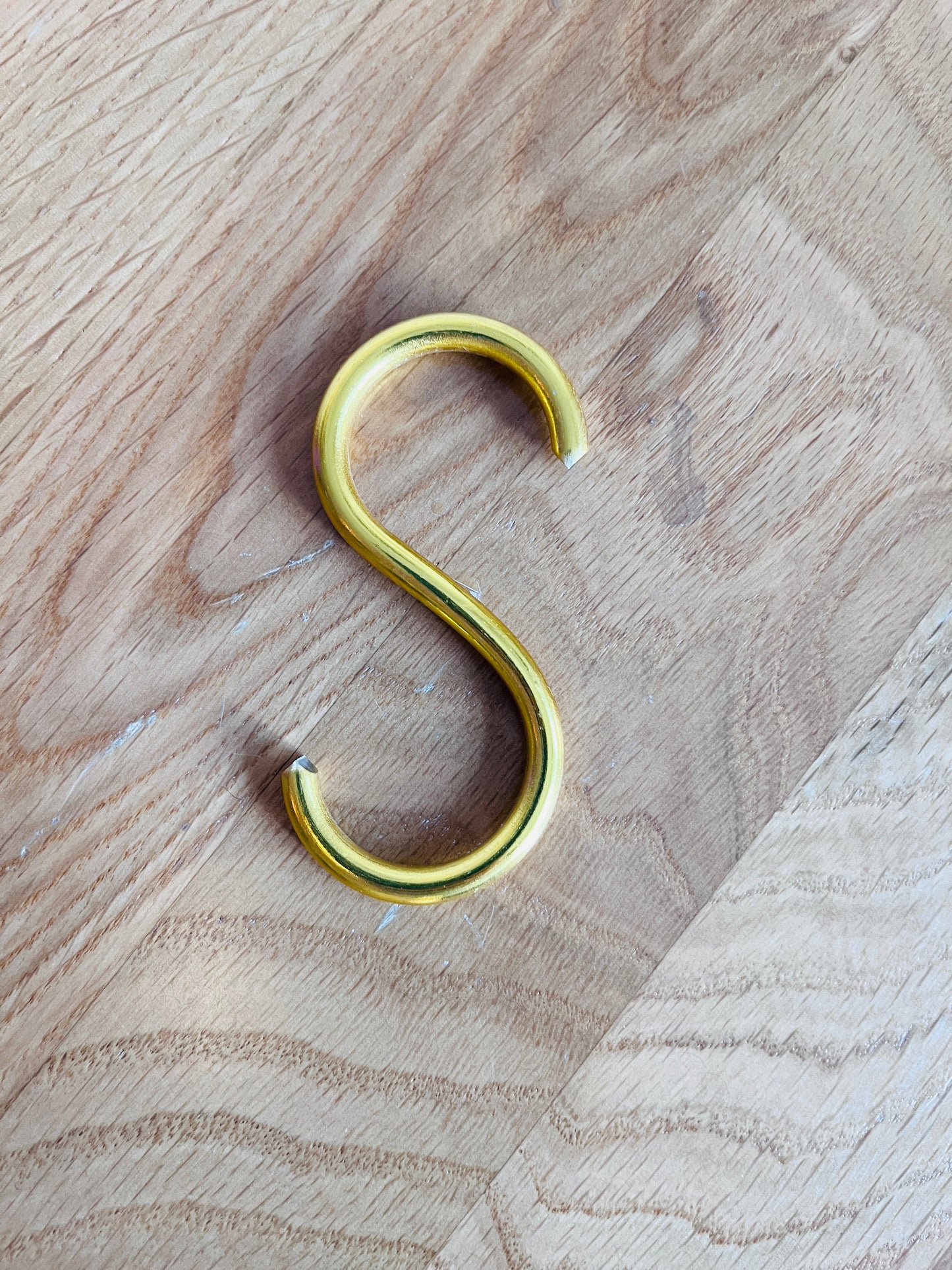 Gold S-hook on a wooden surface
