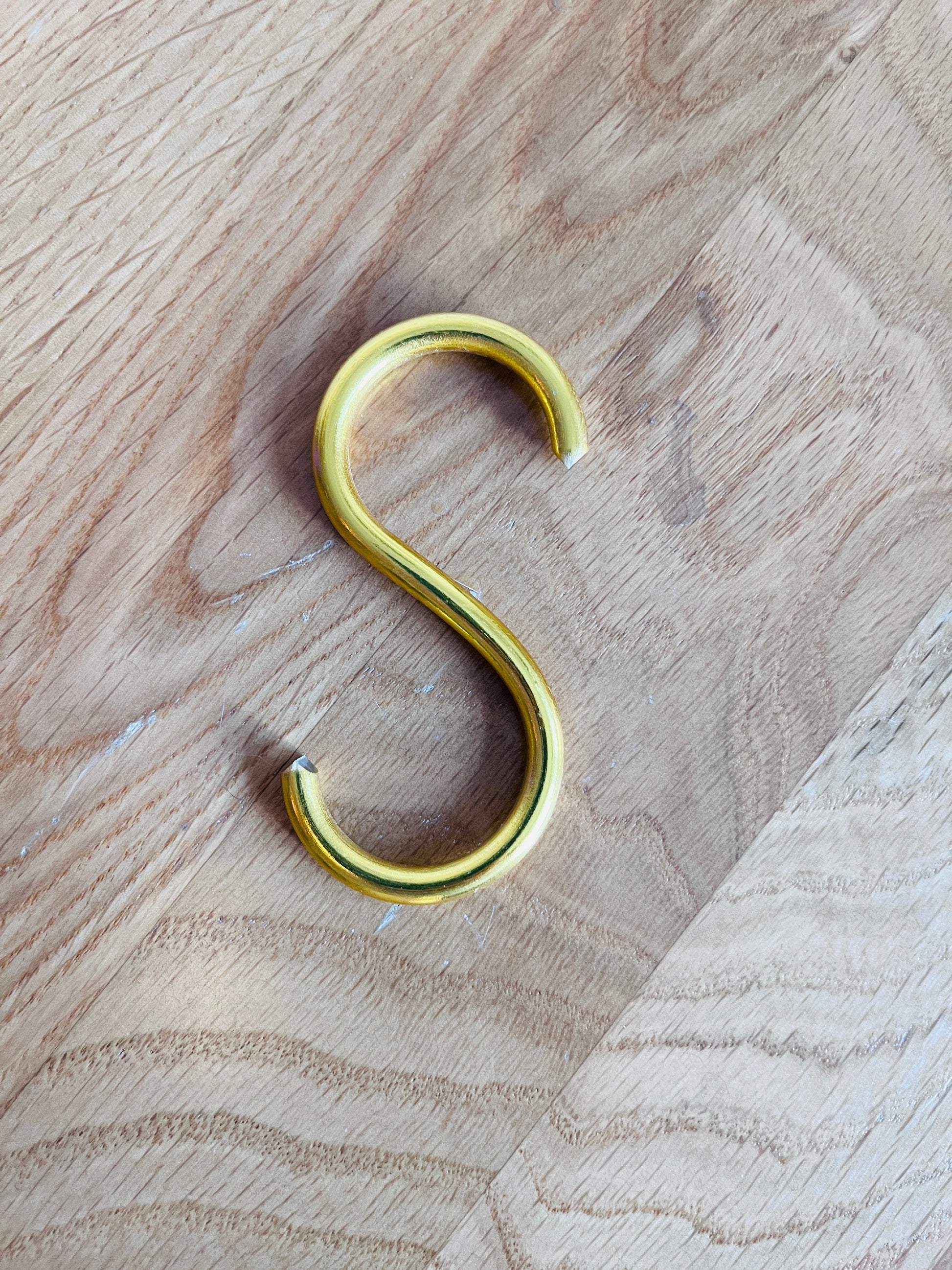 Gold S-hook on a wooden surface