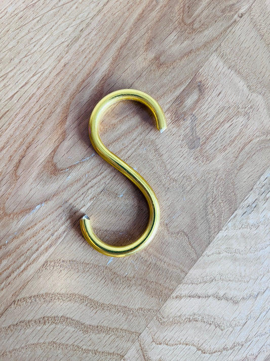 Gold S-hook on a wooden surface